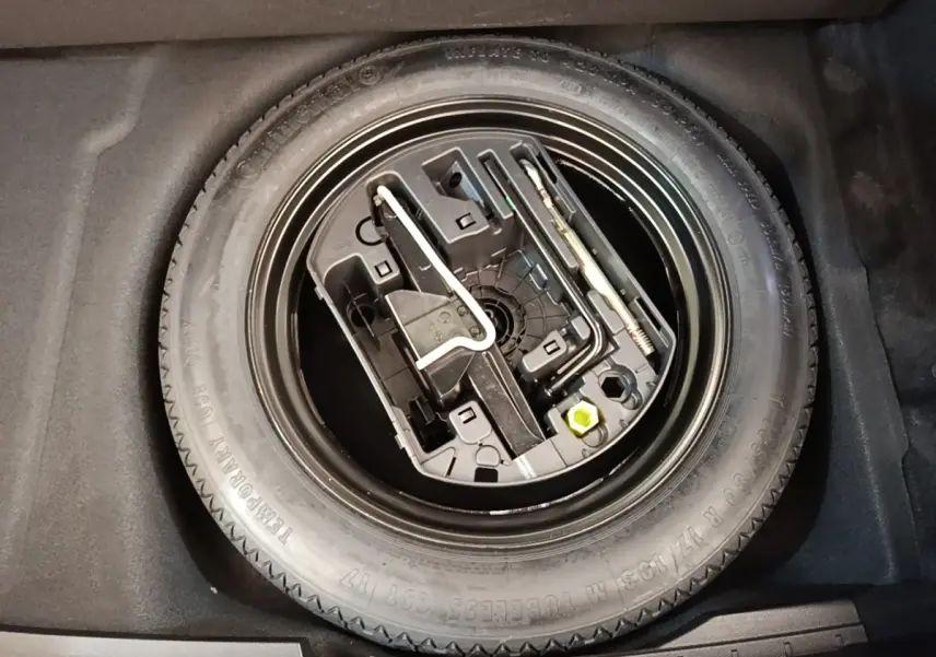 Roue de secours avec kit d'outils intégrés dans le coffre d'une Peugeot 508 gris foncé, vue de dessus.