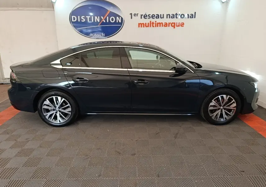 Profil côté gauche d'une Peugeot 508 gris foncé de 2019, avec jantes alliage et vitres teintées, en intérieur showroom.