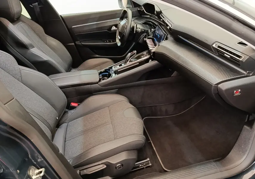 Vue intérieure côté passager de la Peugeot 508 gris foncé, avec tableau de bord moderne et sièges tissu-cuir.
