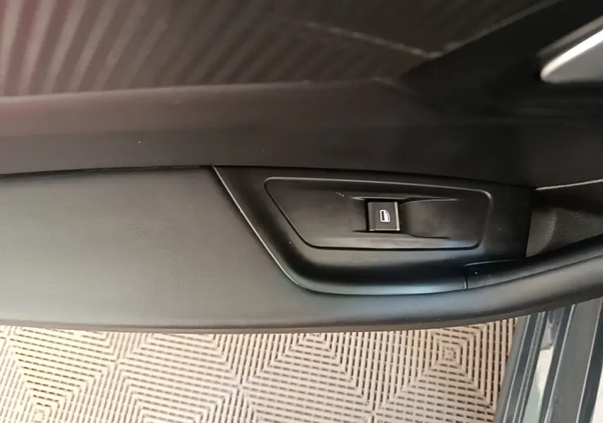 Détail de la commande de lève-vitre côté conducteur sur porte intérieure noire d’une Peugeot 508 gris foncé.