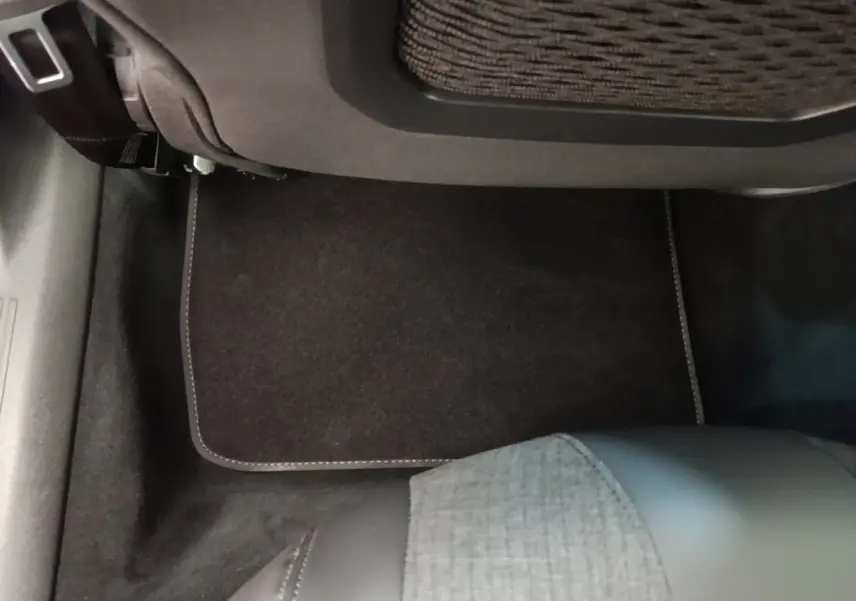 Vue intérieure du plancher arrière droit de la Peugeot 508 gris foncé avec tapis de sol et siège partiel en tissu et cuir.