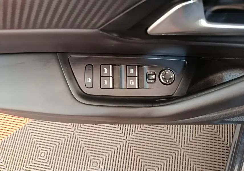 Gros plan sur les commandes de lève-vitres et rétroviseurs côté conducteur d’une Peugeot 508 gris foncé.