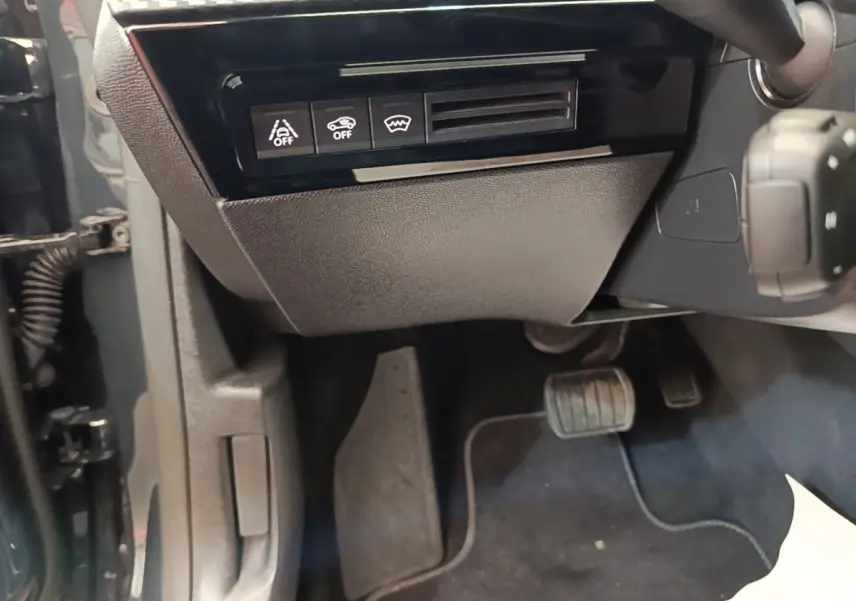 Vue intérieure côté conducteur de la Peugeot 508 gris foncé, avec commandes d'assistance et pédales visibles.
