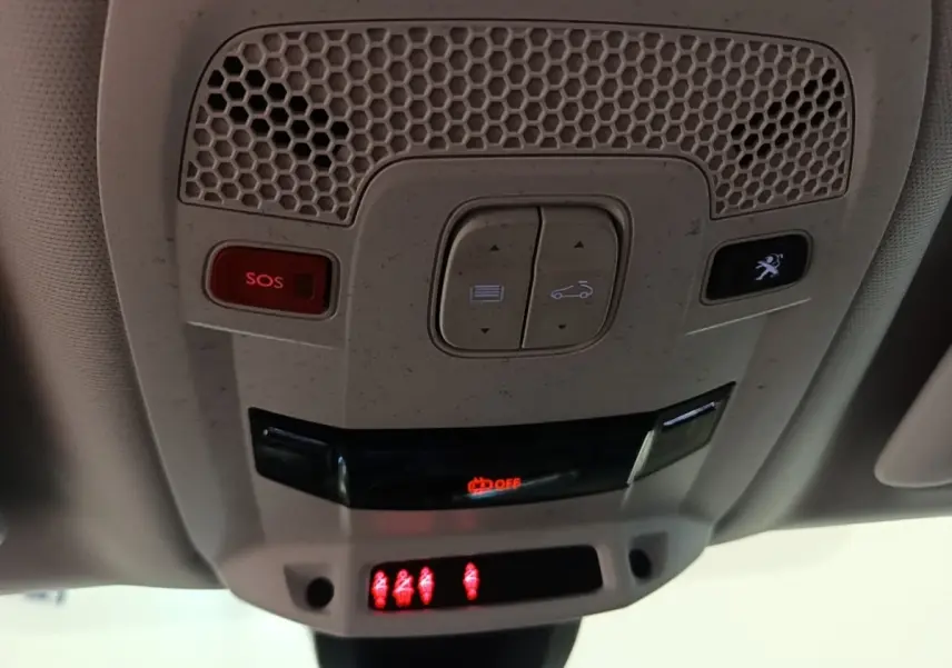 Vue en gros plan du plafonnier gris clair avec boutons SOS et ouverture coffre, éclairage rouge allumé dans une Peugeot 508.