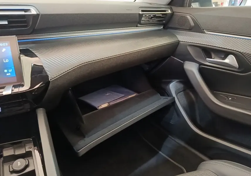 Intérieur de la Peugeot 508 gris foncé, vue côté passager avec boîte à gants ouverte et tableau de bord moderne.