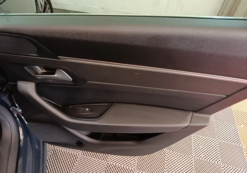 Vue rapprochée de la porte avant gauche de la Peugeot 508 gris foncé, montrant la poignée et les commandes de vitre.