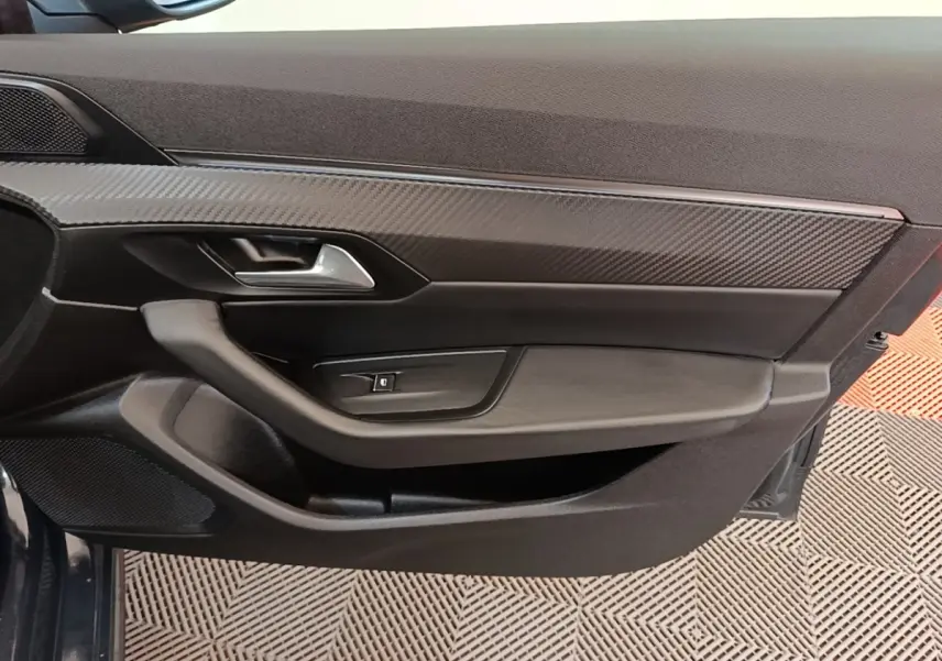 Détail de la porte côté gauche de la Peugeot 508 gris foncé, avec insert effet carbone et poignée argentée.