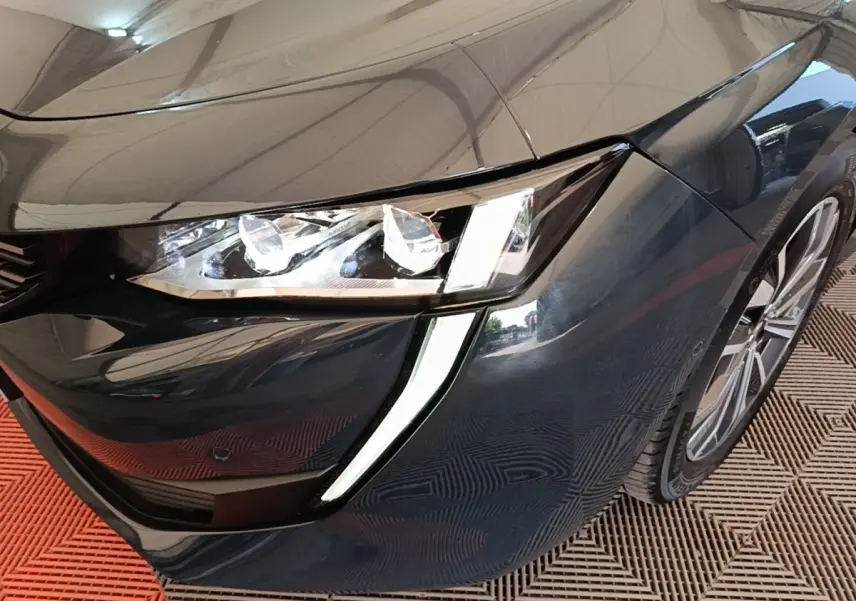 Gros plan sur l'avant droit gris foncé de la Peugeot 508 avec ses phares LED et feux diurnes en forme de griffes.