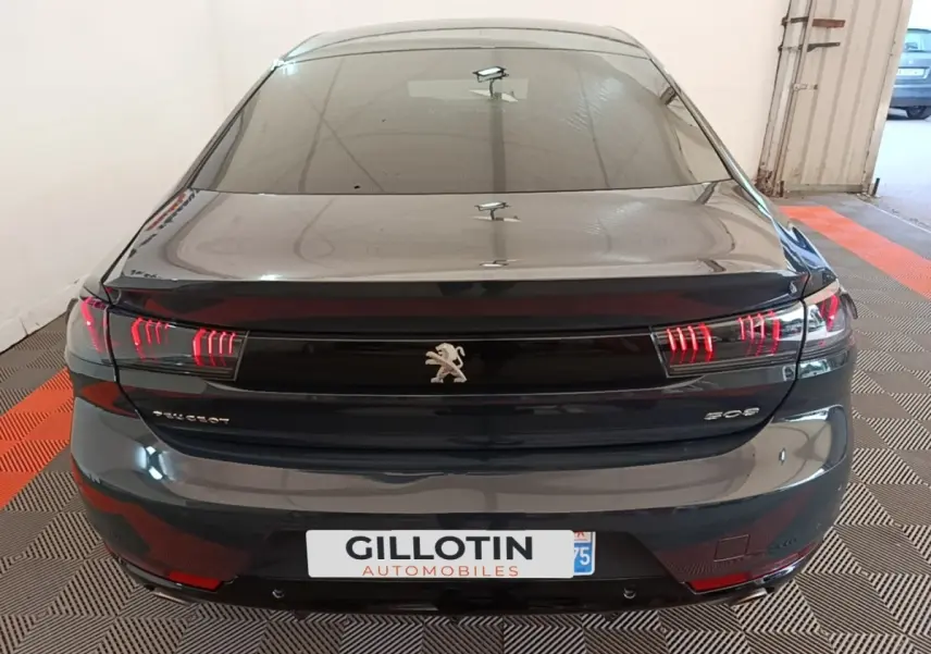 Vue arrière d'une Peugeot 508 gris foncé avec feux arrière LED distinctifs et logo lion central.