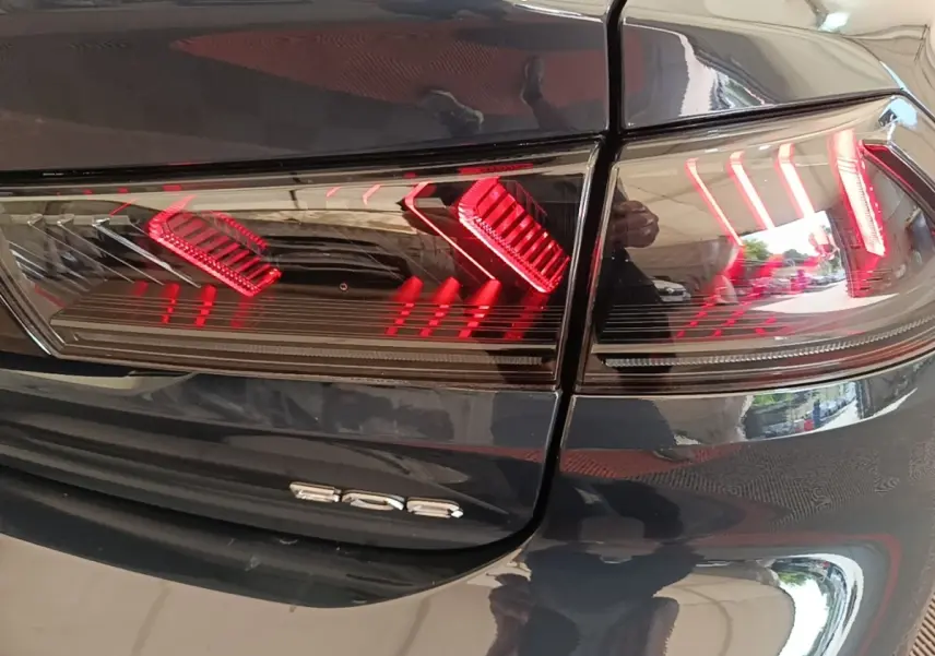 Gros plan sur le feu arrière droit rouge et le logo 508 d’une Peugeot 508 gris foncé, vue arrière.