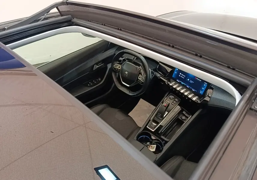 Vue plongeante sur l’intérieur noir de la Peugeot 508 gris foncé, avec tableau de bord digital et toit ouvrant.