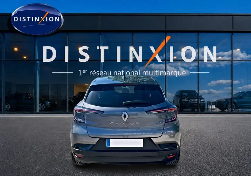 Vue arrière d'un Renault Captur gris cassiopée garé devant une vitrine avec logo Distinxion.
