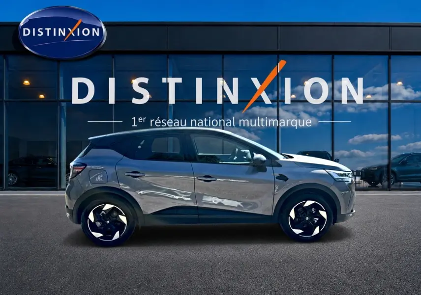 Profil droit du Renault Captur gris cassiopée 2026 devant une vitrine avec logo Distinxion.