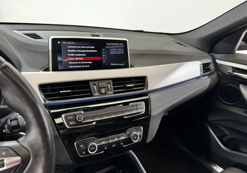 Intérieur BMW X2 xDrive25e 2022 vu côté conducteur, tableau de bord avec écran central et commandes climatisation.