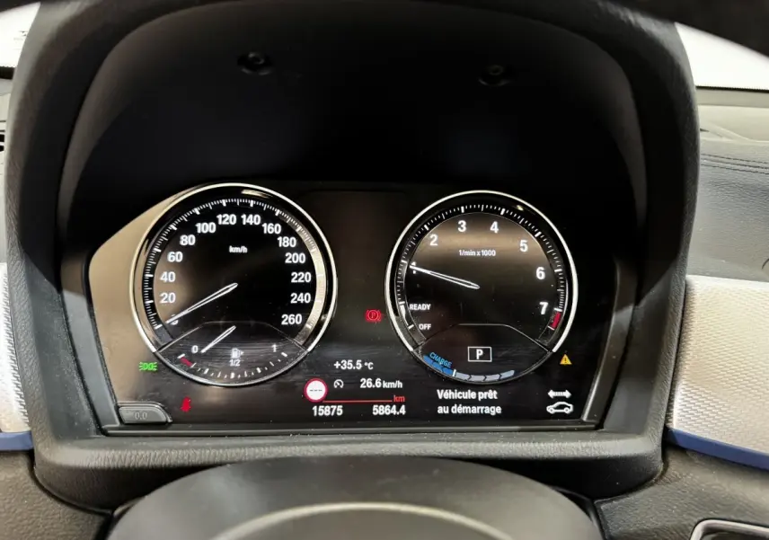 Vue rapprochée du tableau de bord numérique de la BMW X2 blanc, affichant vitesse et compte-tours.