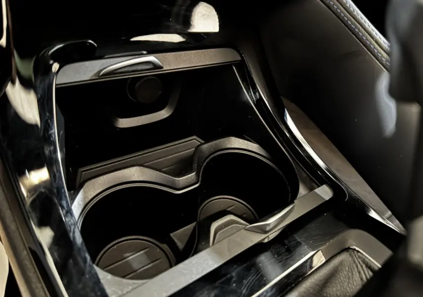 Gros plan sur les porte-gobelets noirs au centre de la console intérieure du BMW X2 xDrive25e blanc.