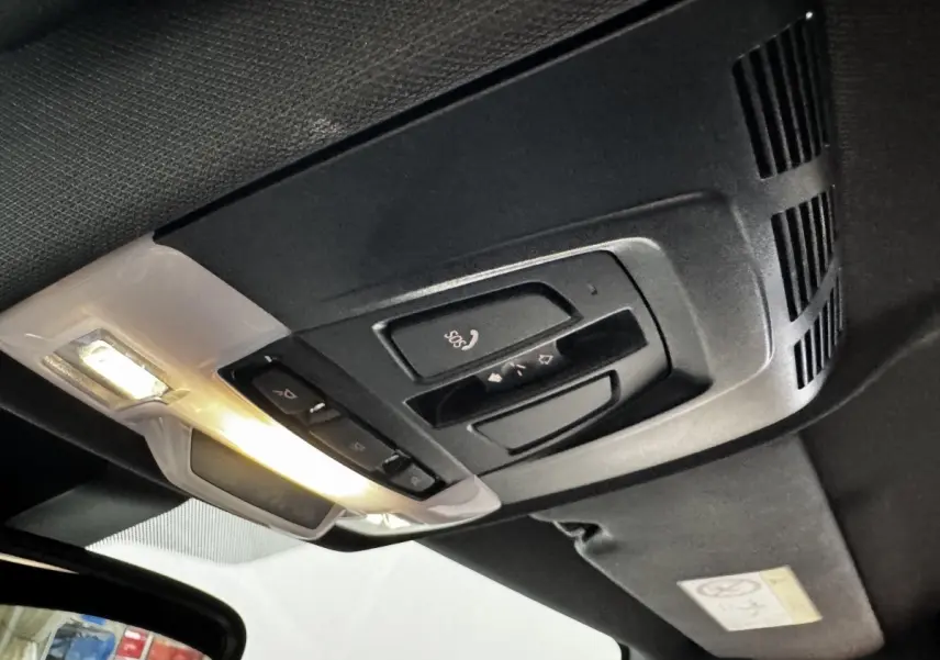 Plafonnier intérieur noir avec commandes SOS et éclairage, vue du toit d’un BMW X2 hybride rechargeable.