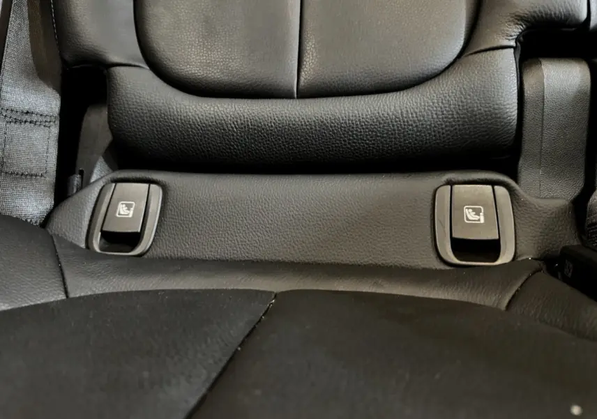 Détail des commandes de rabattement des sièges arrière en cuir noir dans une BMW X2 blanche hybride rechargeable.
