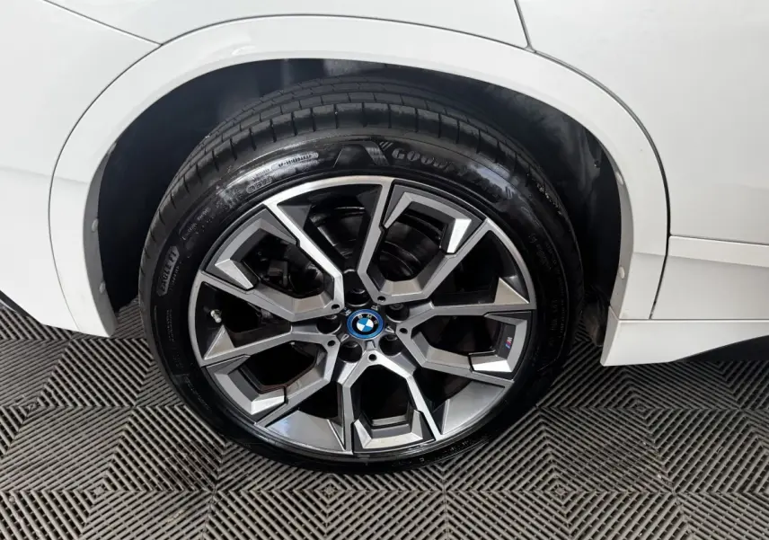 Gros plan sur la roue avant droite d’un BMW X2 blanc, avec jante alliage et logo M Sport visible.