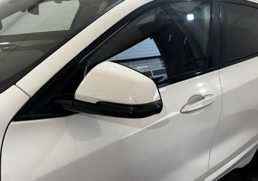 Gros plan sur la porte côté gauche et le rétroviseur blanc d’un BMW X2 xDrive25e M Sport 2022 hybride rechargeable.