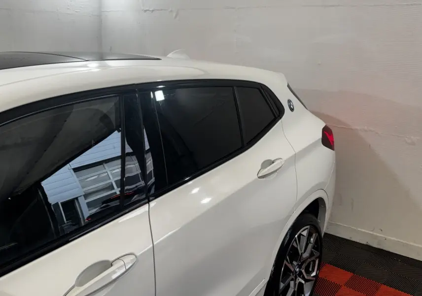 Vue côté droit arrière d'un BMW X2 xDrive25e blanc avec vitres teintées et jantes alliage distinctives.