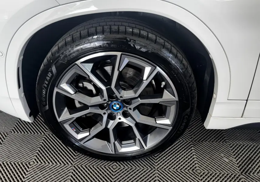 Gros plan sur la roue avant droite d’un BMW X2 blanc avec jante alliage M Sport à design géométrique.