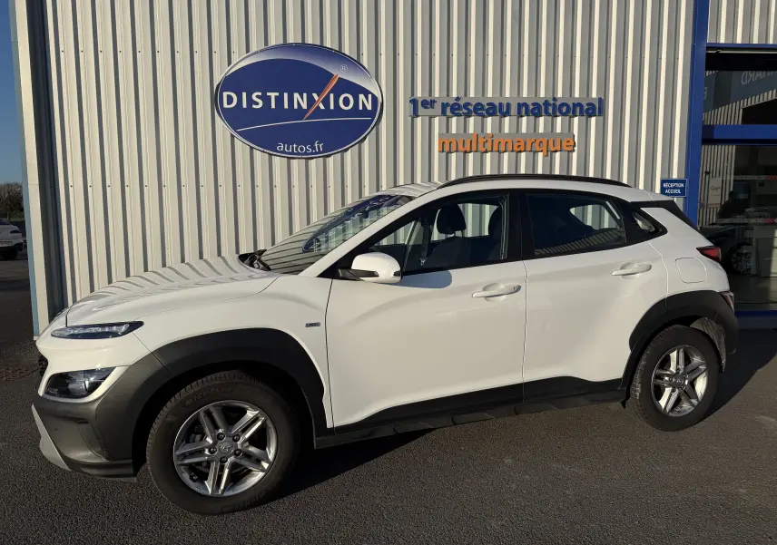 Vue de profil côté gauche d'un Hyundai Kona blanc Atlas avec jantes alliage et protections noires sur les passages de roues.