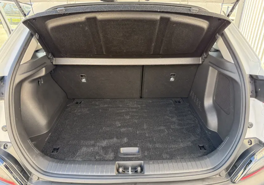 Coffre ouvert vu de l'arrière du Hyundai Kona blanc Atlas 2021, espace de chargement propre et vide.