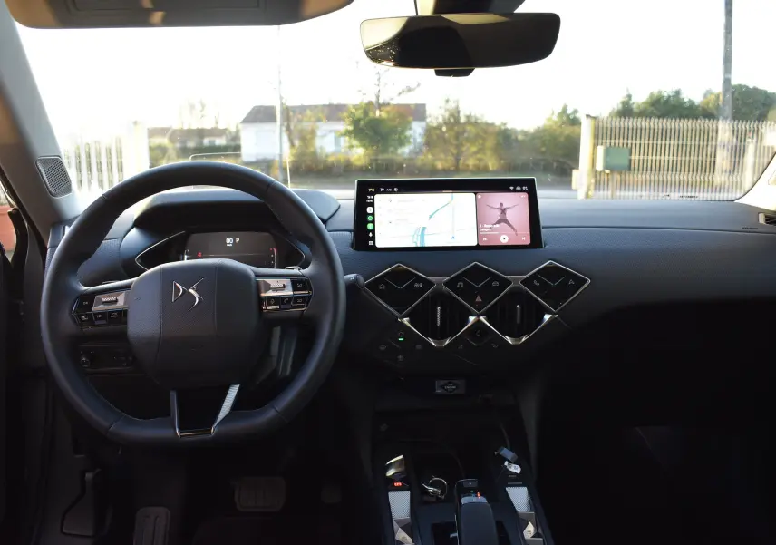 Vue intérieure avant du DS3 Crossback 2024, tableau de bord noir avec écran tactile large et commandes en losange.
