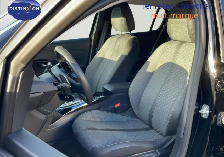 Vue intérieure côté conducteur de la Peugeot 208 noire 2025, sièges tissu gris avec détails cuir et volant multifonction.