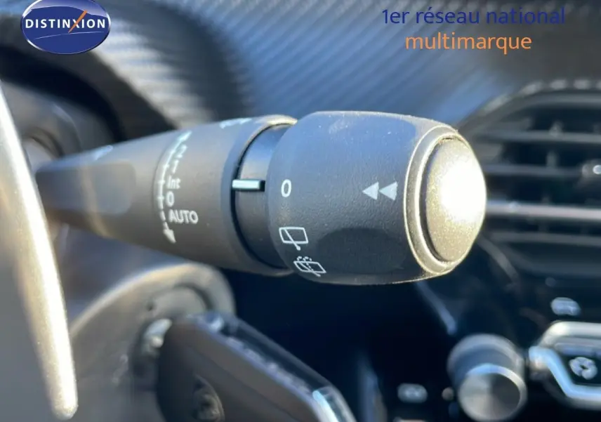Gros plan sur la commande d’essuie-glace à gauche du volant dans l’habitacle noir d’une Peugeot 208 1.2 Hybrid 2025.