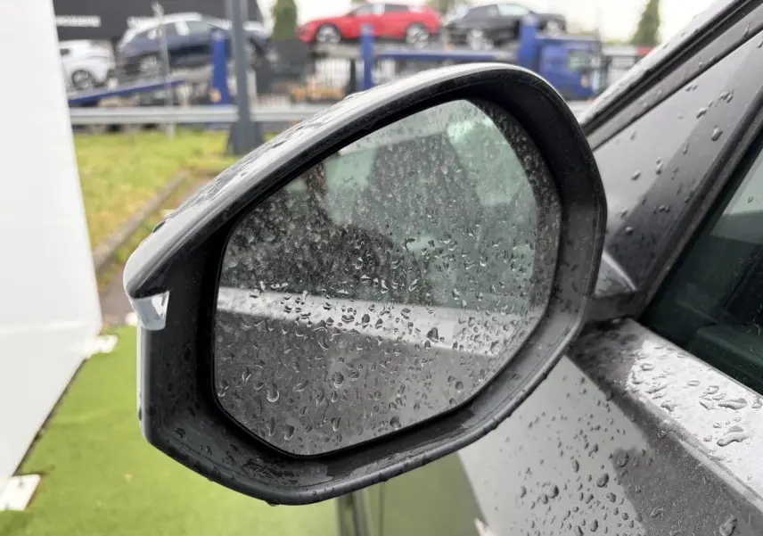 Rétroviseur extérieur côté gauche d'une Citroën C5 Aircross platinium avec toit noir, vue rapprochée sous la pluie.