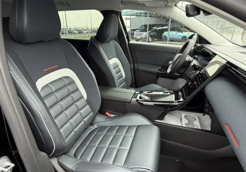 Vue intérieure côté conducteur du Citroën C5 Aircross 2026, sièges noirs matelassés avec inserts gris et touches rouges.