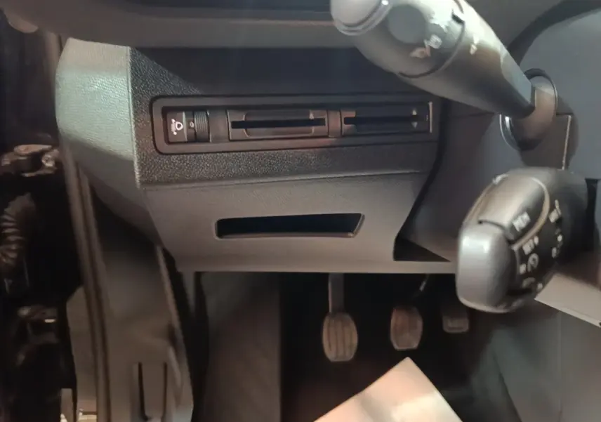 Détail de la partie inférieure du tableau de bord côté conducteur du Peugeot 5008 noir, avec pédales et commandes au volant visibles.