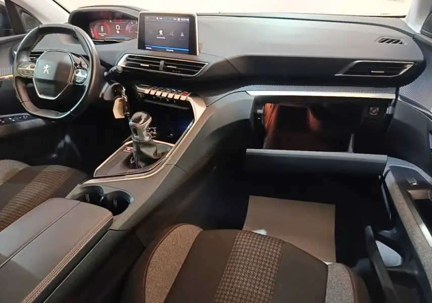 Intérieur Peugeot 5008 2018 noir, vue côté passager montrant tableau de bord, écran tactile et boîte manuelle ouverte.