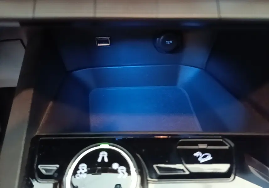 Gros plan sur la console centrale noire du Peugeot 5008, avec molette de sélection des modes de conduite et prise 12V visible.
