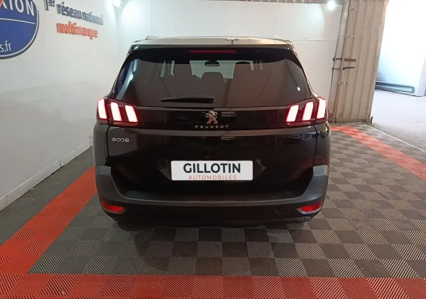 Vue arrière d’un Peugeot 5008 noir avec feux LED caractéristiques allumés dans un garage.