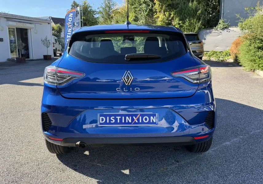 Vue arrière d'une Renault Clio Evolution TCe 90 bleu 2024 avec feux LED et logo distinctif sur parking extérieur.