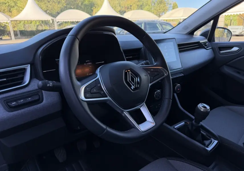 Intérieur de la Renault Clio Evolution TCe 90 2024, vue côté conducteur sur volant cuir et écran tactile central.