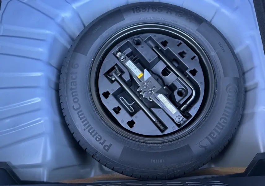 Vue rapprochée de la roue de secours et des outils de bord dans le coffre d’une Renault Clio Evolution TCe 90 bleu 2024.