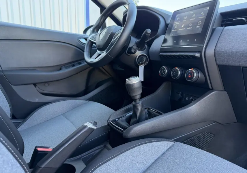 Vue intérieure côté conducteur de la Renault Clio Evolution TCe 90 2024, avec volant cuir, écran tactile et sièges gris.
