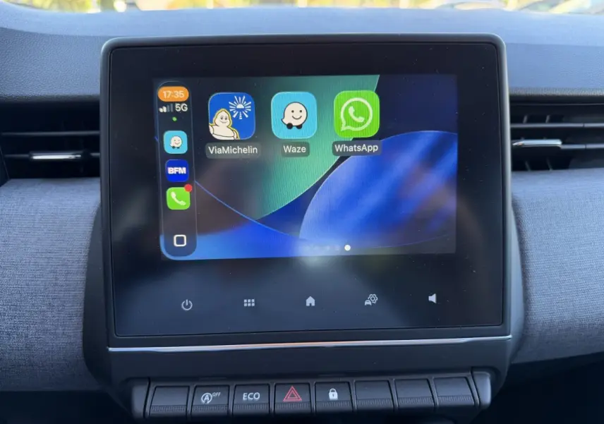 Écran tactile central affichant des applications de navigation et messagerie dans l'habitacle d'une Renault Clio bleu 2024.