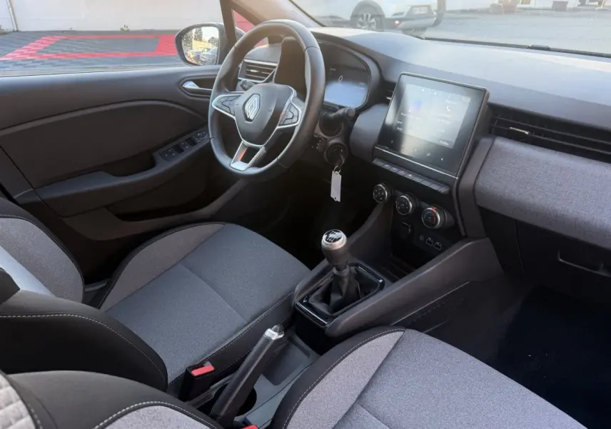 Vue intérieure côté conducteur de la Renault Clio Evolution TCe 90 2024, volant cuir, écran tactile et levier de vitesse manuel.