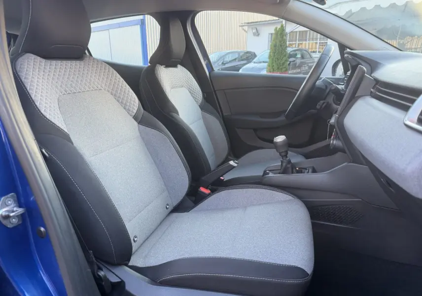 Vue intérieure côté conducteur de la Renault Clio Evolution TCe 90 bleu, sièges tissu gris et console centrale avec boîte manuelle.