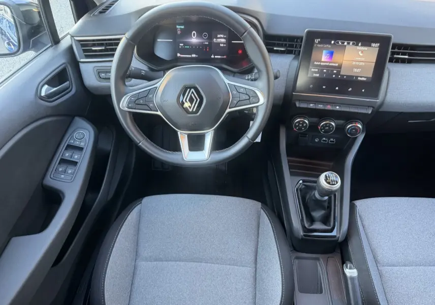 Vue intérieure avant de la Renault Clio Evolution TCe 90 2024, volant cuir, écran tactile et levier de vitesses manuel.