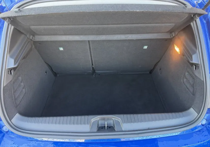 Coffre ouvert vu de dessus d'une Renault Clio Evolution TCe 90 bleu 2024, espace de rangement vide et éclairage intérieur allumé.