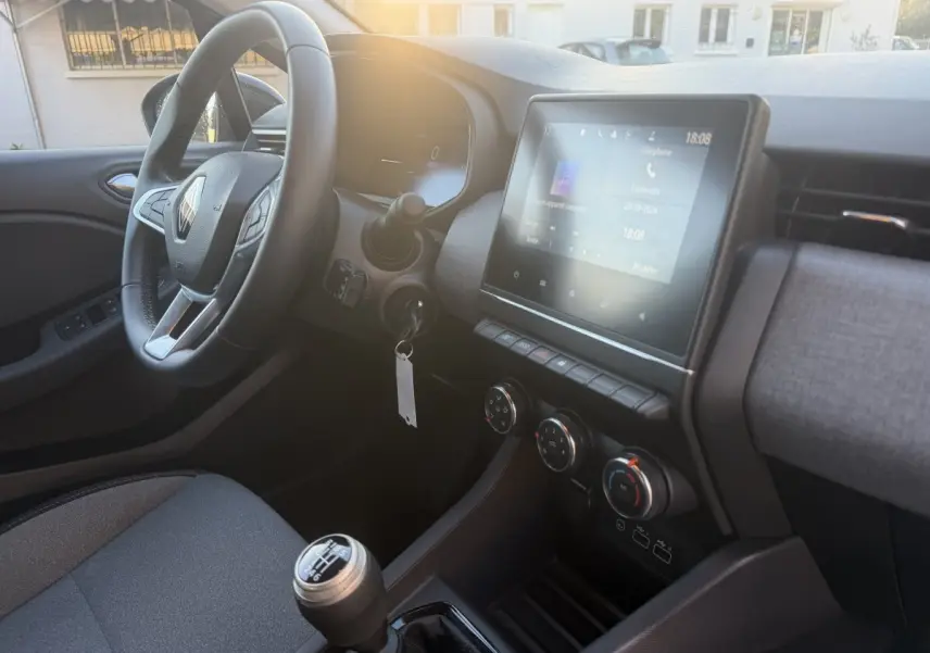 Vue intérieure côté conducteur de la Renault Clio Evolution TCe 90 2024, volant cuir et écran tactile central allumé.