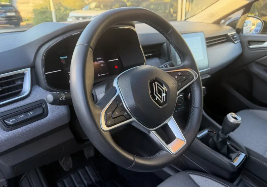 Vue intérieure centrée sur le volant cuir multifonctions et la boîte manuelle de la Renault Clio Evolution TCe 90 2024.