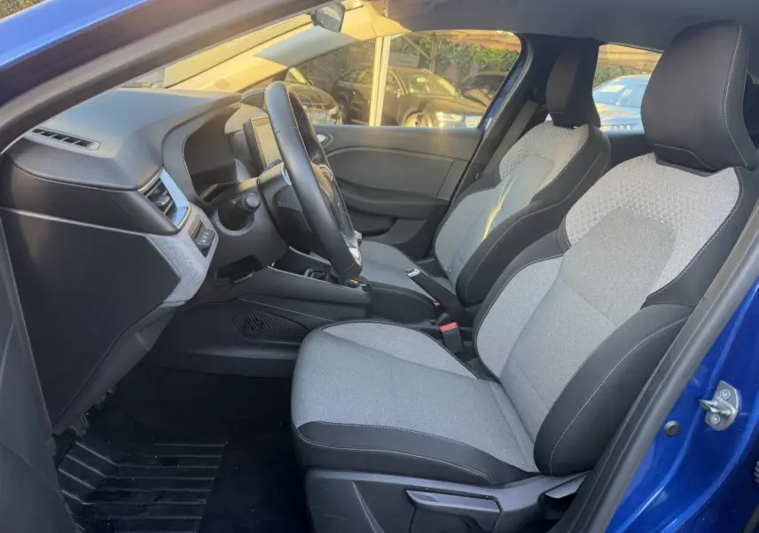 Vue intérieure côté conducteur de la Renault Clio Evolution TCe 90 2024 bleu, sièges tissu gris et noir, volant multifonctions.