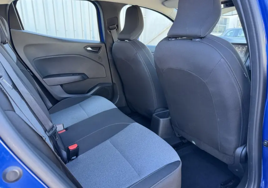 Vue intérieure arrière côté gauche de la Renault Clio Evolution TCe 90 2024 bleu, sièges tissu bicolore gris et noir.